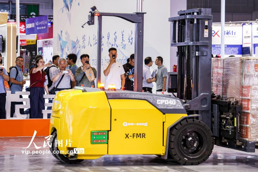 第24屆中國工博會現(xiàn)場，觀眾觀看叉取機(jī)器人作業(yè)演示。王初攝（人民圖片網(wǎng)）