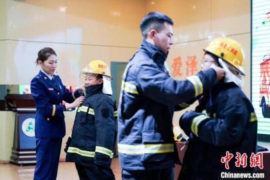 圖為學生們現(xiàn)場穿戴消防頭盔和戰(zhàn)斗服。中新社記者 趙宇航 攝