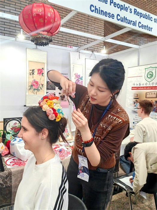 展覽正值羅馬尼亞迎春花節(jié)，國際中文教師志愿者潘婧穎向游客們介紹了國家非物質(zhì)文化遺產(chǎn)——福建泉州的簪花文化。布加勒斯特大學(xué)孔子學(xué)院供圖。
