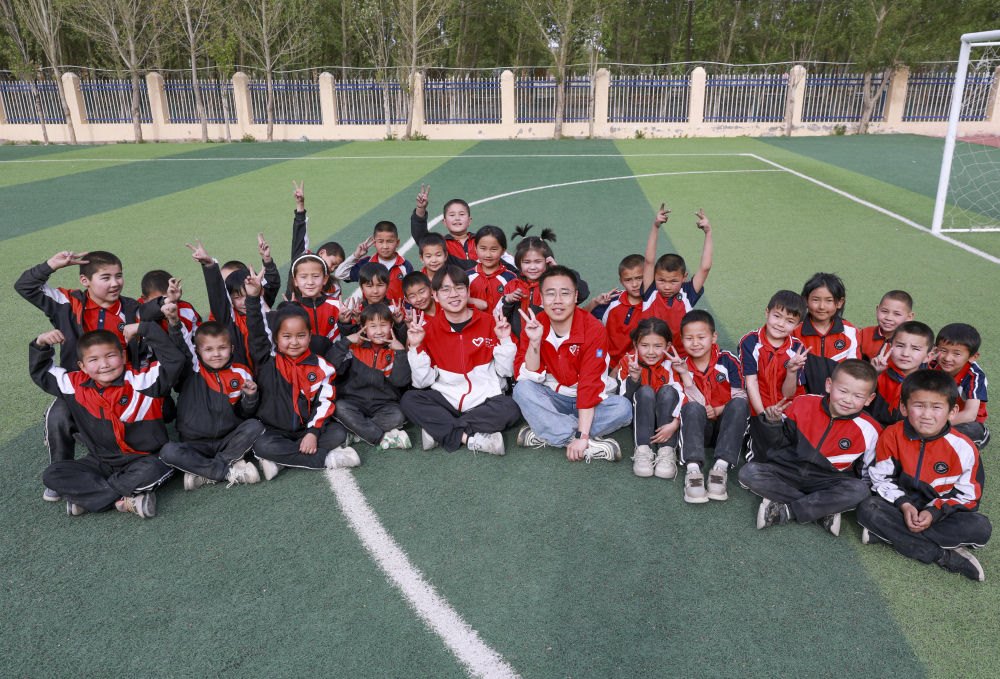 4月23日，在新疆克州阿圖什市哈拉峻鄉(xiāng)謝依特小學(xué)，支教教師王俊文（中左）、李軻凡（中右）和學(xué)生在一起。