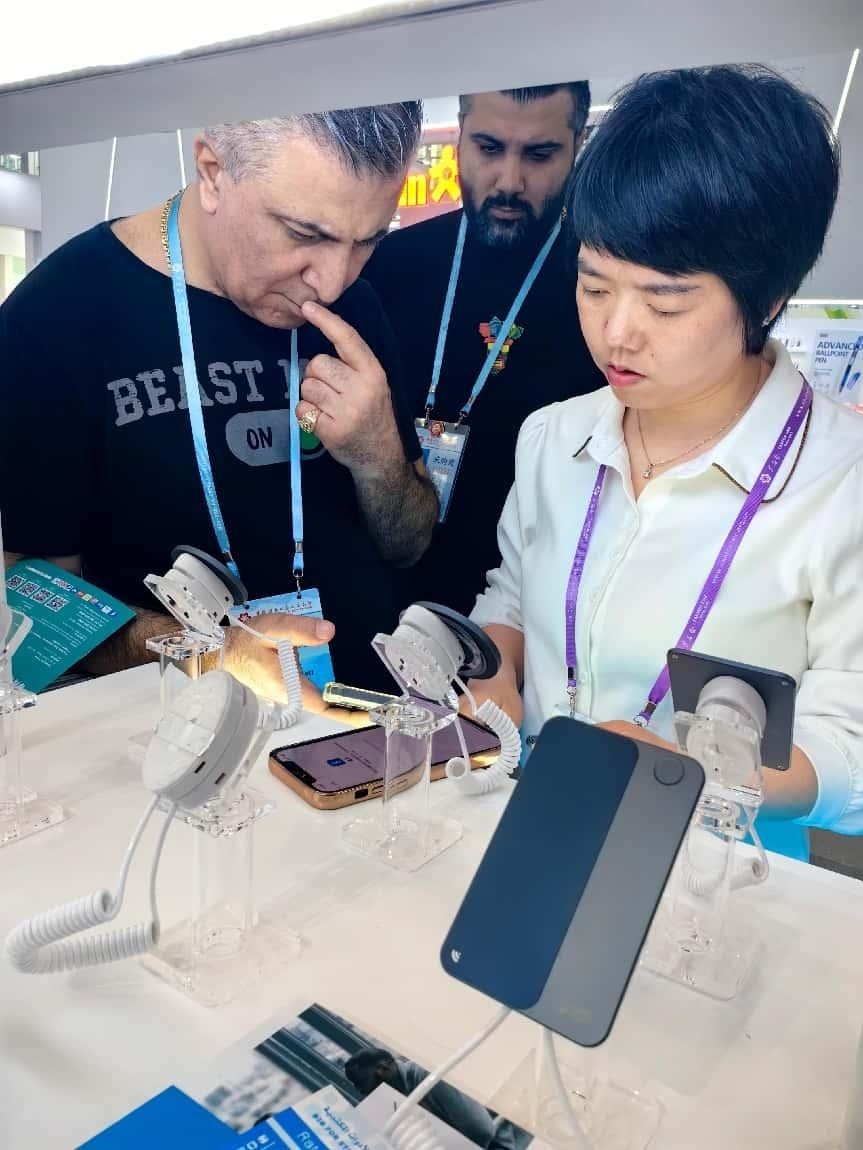 展臺(tái)工作人員向外商展示“AI TOP翻譯終端”。圖片來源：受訪者提供