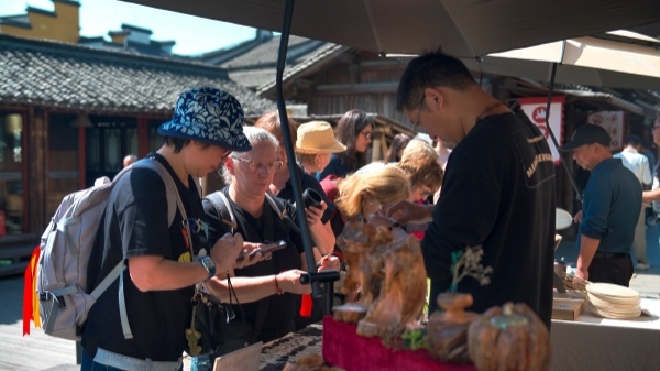 “五一”期間，游客正在烏鎮(zhèn)“水鄉(xiāng)碼頭”挑選購買文創(chuàng)產(chǎn)品。受訪者供圖