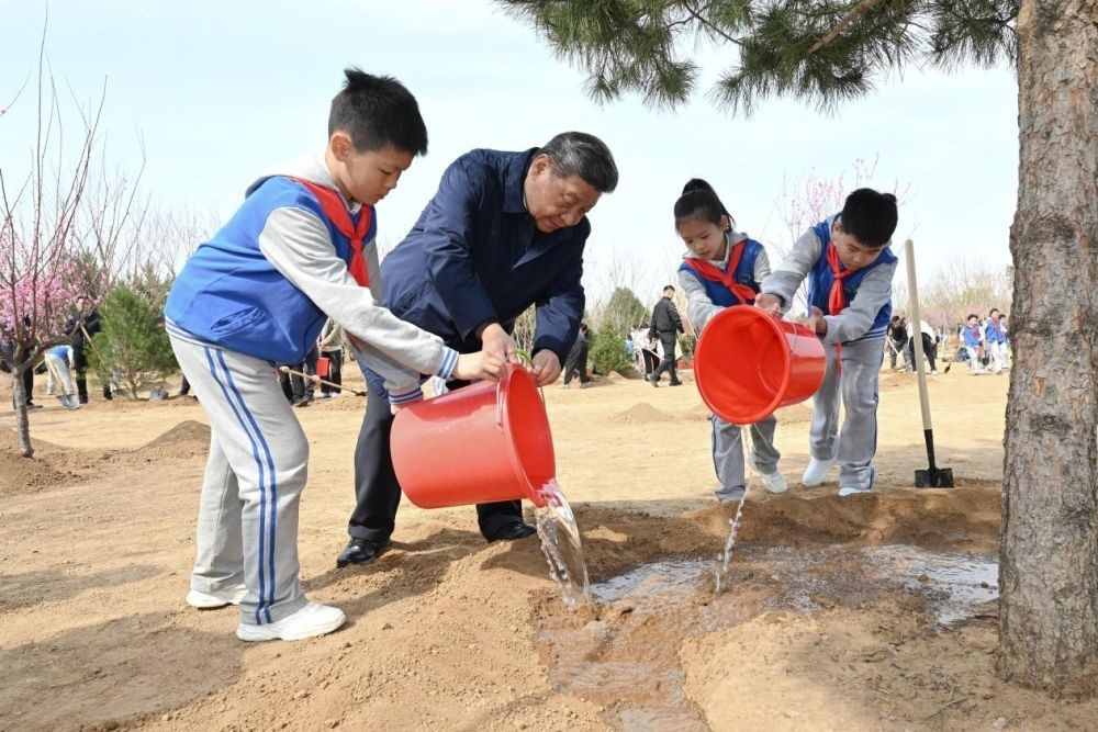 2025年4月3日，習(xí)近平總書記等來到北京市豐臺區(qū)永定河畔參加首都義務(wù)植樹活動。這是習(xí)近平總書記同少先隊員一起給剛栽下的樹苗澆水。新華社記者 謝環(huán)馳 攝